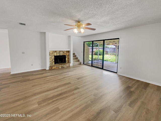 1127 Romaine Cir W, Jacksonville, FL 32225 - unfurnished living room with a textured ceiling, a ceiling fan, wood finished floors, baseboards, and a stone fireplace