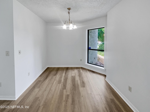 1127 Romaine Cir W, Jacksonville, FL 32225 - spare room with wood finished floors, a chandelier, a textured ceiling, and baseboards