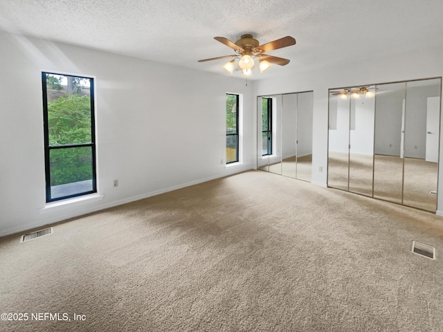 1127 Romaine Cir W, Jacksonville, FL 32225 - unfurnished bedroom with two closets, a textured ceiling, carpet flooring, baseboards, and a ceiling fan