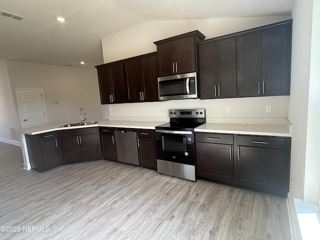8322 Helmsley Blvd, Jacksonville, FL 32219 - kitchen featuring stainless steel appliances, a sink, vaulted ceiling, a peninsula, and light wood-type flooring