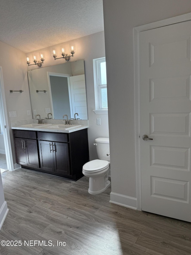 8322 Helmsley Blvd, Jacksonville, FL 32219 - bathroom with double vanity, baseboards, toilet, wood finished floors, and a textured ceiling