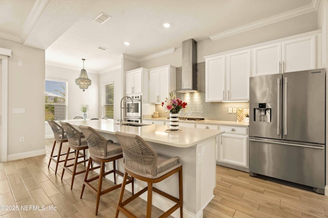 228 Waterline Dr, Saint Johns, FL 32259 - kitchen featuring appliances with stainless steel finishes, wall chimney exhaust hood, a sink, light wood-type flooring, and an island with sink