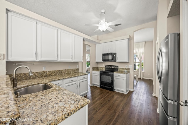 528 Sparrow Branch Cir, Saint Johns, FL 32259 - kitchen with black appliances, a sink, arched walkways, light stone counters, and white cabinetry
