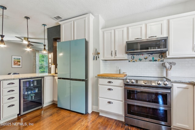4241 Lexington Ave, Jacksonville, FL 32210 - kitchen featuring stainless steel appliances, beverage cooler, a peninsula, white cabinets, and a textured ceiling