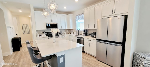 55 Fairlake Cir, Saint Augustine, FL 32092 - kitchen featuring stainless steel appliances, a sink, decorative backsplash, white cabinets, and light wood-style flooring