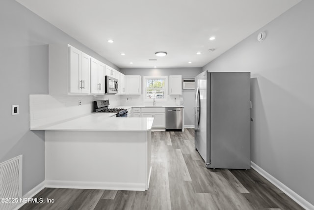 2155 Diana Dr, Palatka, FL 32177 - kitchen with stainless steel appliances, a sink, light wood-type flooring, a peninsula, and white cabinetry