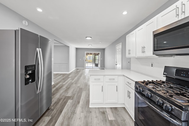 2155 Diana Dr, Palatka, FL 32177 - kitchen featuring stainless steel appliances, white cabinetry, light countertops, a peninsula, and light wood-style floors
