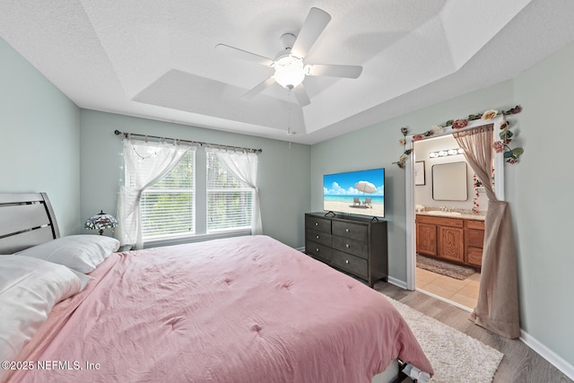 8609 Victoria Falls Dr, Jacksonville, FL 32244 - bedroom with a tray ceiling, light wood-style flooring, a sink, baseboards, and ensuite bathroom