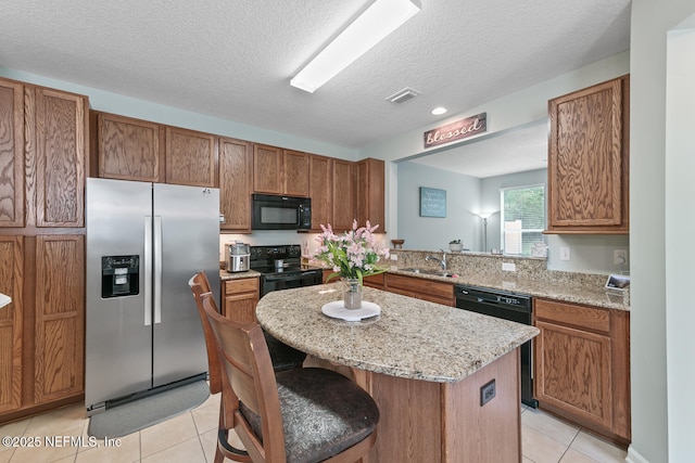 8609 Victoria Falls Dr, Jacksonville, FL 32244 - kitchen with black appliances, a sink, light tile patterned flooring, a kitchen island, and brown cabinetry