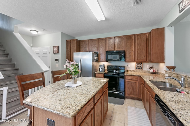8609 Victoria Falls Dr, Jacksonville, FL 32244 - kitchen with black appliances, a sink, light stone countertops, brown cabinets, and a textured ceiling