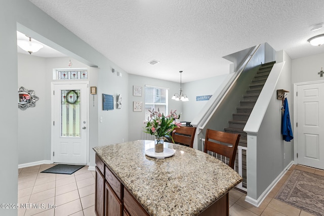 8609 Victoria Falls Dr, Jacksonville, FL 32244 - kitchen featuring light tile patterned floors, baseboards, a chandelier, a kitchen island, and light stone counters