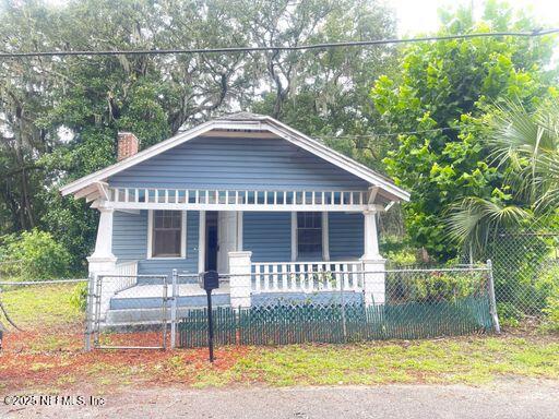 594 E 60th St, Jacksonville, FL 32208 - bungalow-style home featuring covered porch, a chimney, and a fenced front yard