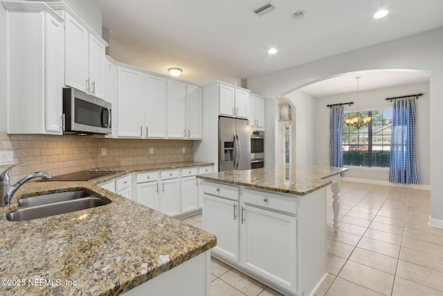 33146 Prairie Parke Pl, Fernandina Beach, FL 32034 - kitchen with stainless steel appliances, a sink, a chandelier, arched walkways, and decorative backsplash