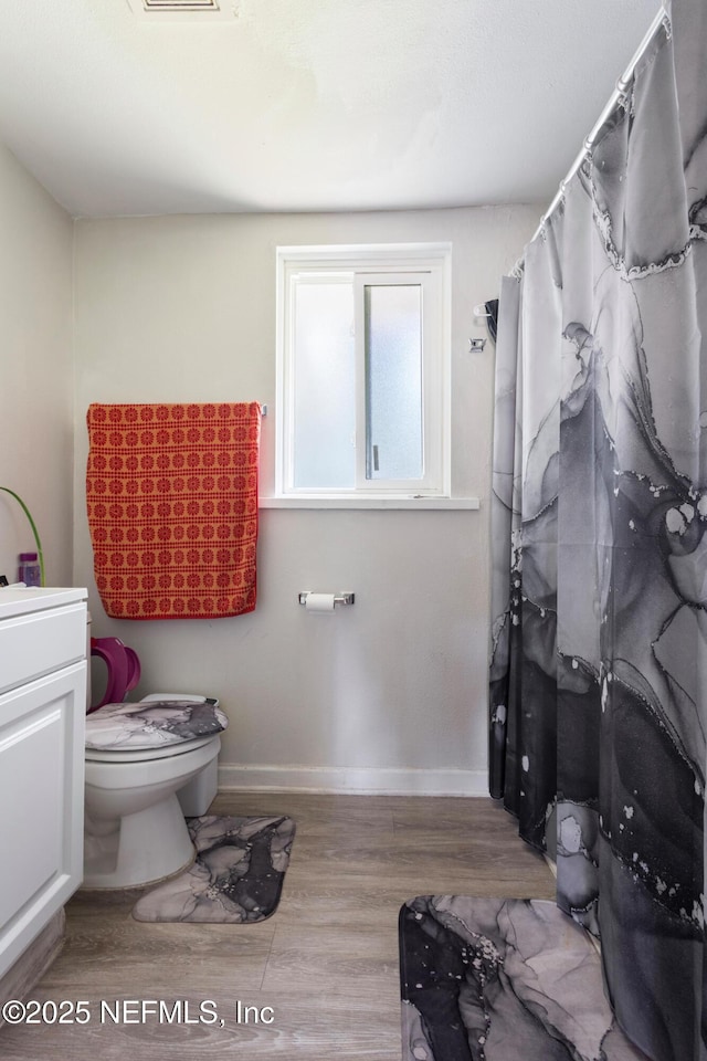 2780 Paul Ave, Jacksonville, FL 32207 - full bath with wood finished floors, baseboards, toilet, vanity, and a shower with curtain