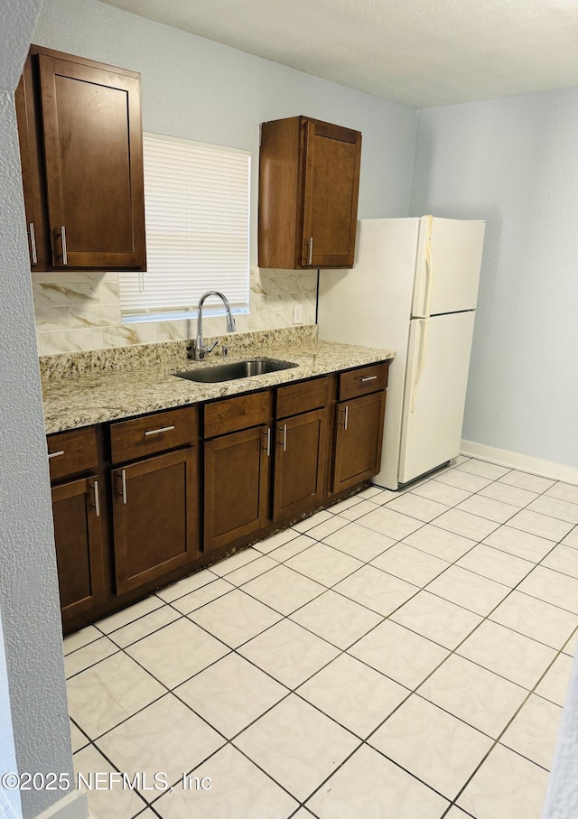 1556 Logan St, Jacksonville, FL 32209 - kitchen featuring a sink, freestanding refrigerator, dark brown cabinets, and light stone countertops