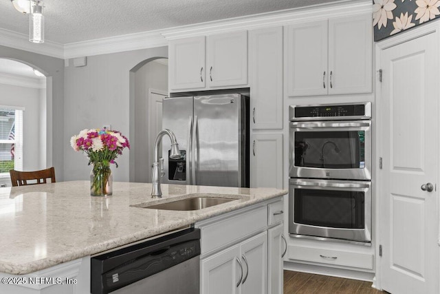 356 Heron Landing Rd, Saint Johns, FL 32259 - kitchen featuring stainless steel appliances, arched walkways, crown molding, dark wood-type flooring, and white cabinetry