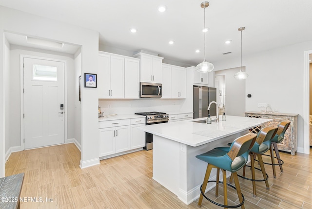 109 Fly Line Dr, Saint Johns, FL 32259 - kitchen with appliances with stainless steel finishes, light wood-style flooring, a center island with sink, a kitchen bar, and a sink