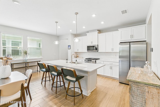 109 Fly Line Dr, Saint Johns, FL 32259 - kitchen featuring appliances with stainless steel finishes, backsplash, light wood-style floors, an island with sink, and light countertops