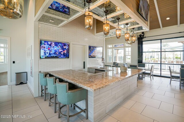 109 Fly Line Dr, Saint Johns, FL 32259 - kitchen featuring light tile patterned floors, a chandelier, a towering ceiling, light stone countertops, and hanging light fixtures