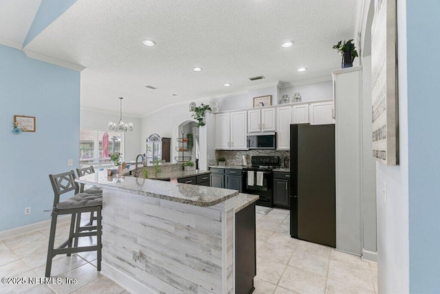2918 Grande Oaks Way, Fleming Island, FL 32003 - kitchen featuring black / electric stove, stainless steel microwave, freestanding refrigerator, ornamental molding, and a large island