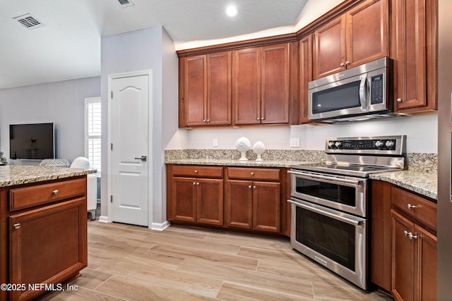 271 Roaring Brook Dr, Saint Augustine, FL 32084 - kitchen featuring stainless steel appliances, light stone counters, wood finish floors, and brown cabinets