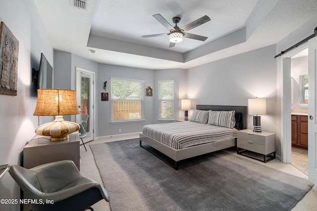 271 Roaring Brook Dr, Saint Augustine, FL 32084 - bedroom featuring light carpet, a tray ceiling, a barn door, ensuite bathroom, and a textured ceiling