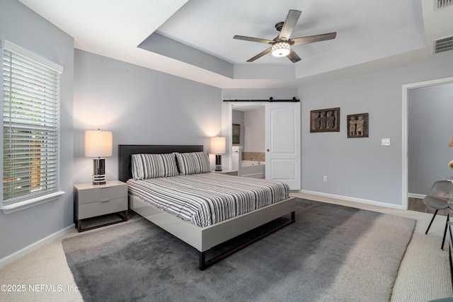271 Roaring Brook Dr, Saint Augustine, FL 32084 - carpeted bedroom featuring a barn door, a raised ceiling, baseboards, ceiling fan, and ensuite bath