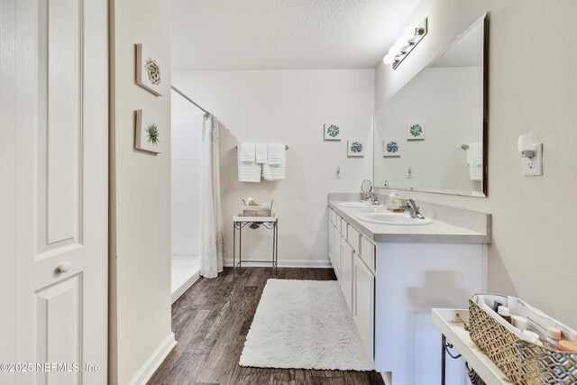 36 Grand Par Ct, Bunnell, FL 32110 - full bath with double vanity, wood finished floors, a shower with shower curtain, baseboards, and a textured ceiling
