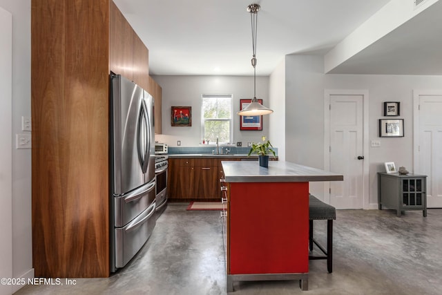 171 Twine St, Saint Augustine, FL 32084 - kitchen featuring appliances with stainless steel finishes, a sink, concrete floors, a breakfast bar area, and brown cabinetry