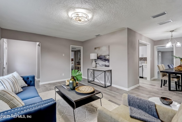 5916 Redberry Ln, Jacksonville, FL 32211 - living room with light wood-style flooring, a textured ceiling, and a chandelier