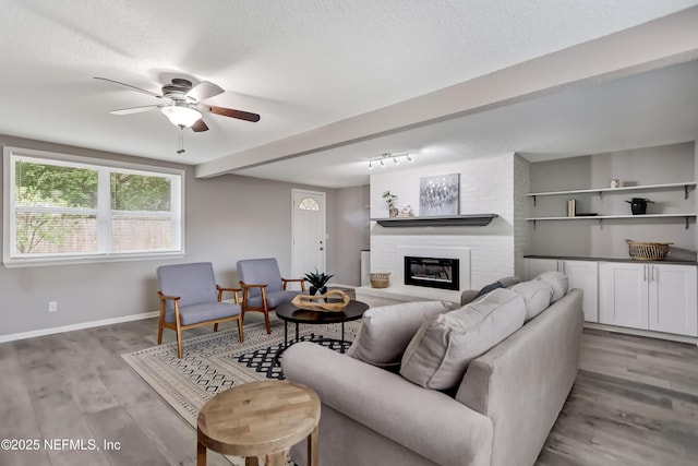 5916 Redberry Ln, Jacksonville, FL 32211 - living room featuring a ceiling fan, a fireplace, light wood-style flooring, and a textured ceiling