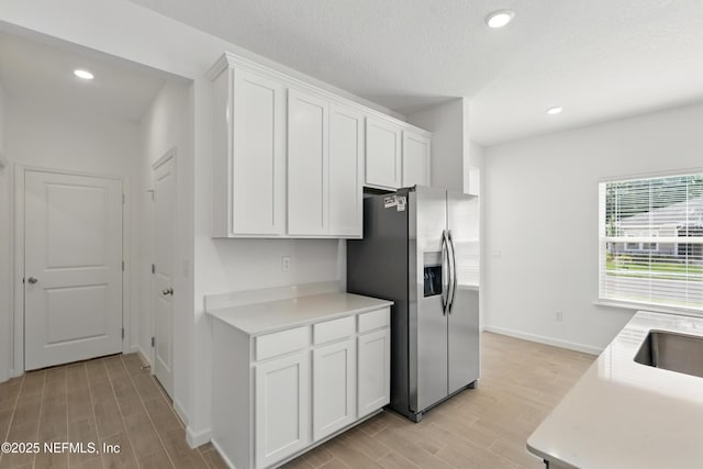 9053 Whinny Way, Jacksonville, FL 32219 - kitchen featuring stainless steel fridge with ice dispenser, light wood-style floors, white cabinets, light countertops, and baseboards