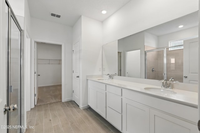 9053 Whinny Way, Jacksonville, FL 32219 - bathroom featuring a stall shower, double vanity, a spacious closet, wood finished floors, and recessed lighting