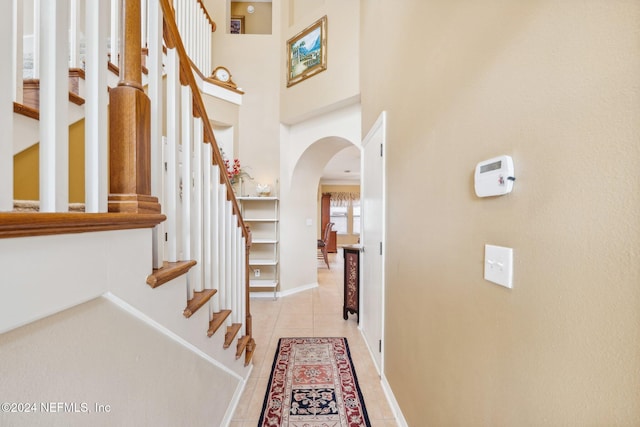 5346 Brighton Park Ln, Jacksonville, FL 32210 - foyer featuring arched walkways, light tile patterned floors, stairs, baseboards, and a high ceiling
