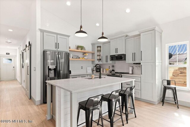 66 Oneida St, Saint Augustine, FL 32084 - kitchen with appliances with stainless steel finishes, a sink, lofted ceiling, decorative backsplash, and light wood-type flooring