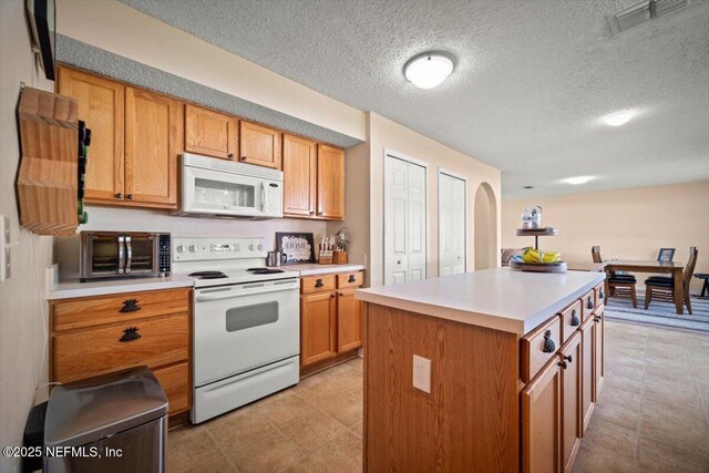 12 Roxland Ln, Palm Coast, FL 32164 - kitchen featuring white appliances, light countertops, a center island, a textured ceiling, and brown cabinetry