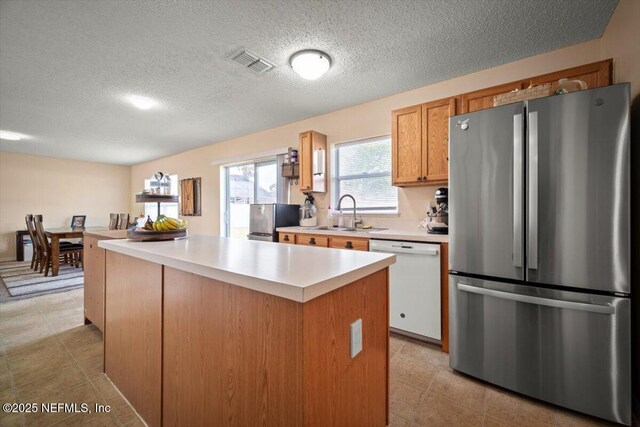 12 Roxland Ln, Palm Coast, FL 32164 - kitchen with freestanding refrigerator, dishwasher, a sink, light countertops, and a center island