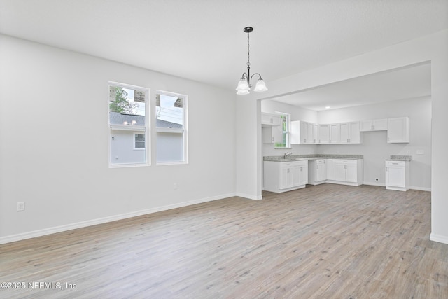 11807 Lem Turner Rd, Jacksonville, FL 32218 - kitchen with a chandelier, white cabinets, light wood-style flooring, baseboards, and a sink