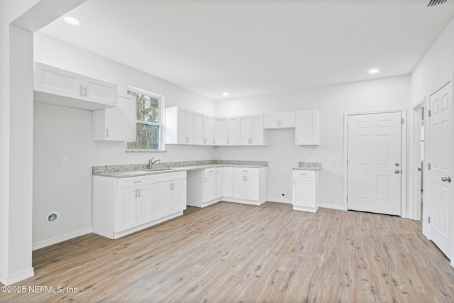 11807 Lem Turner Rd, Jacksonville, FL 32218 - kitchen with a sink, light wood-type flooring, white cabinets, light countertops, and baseboards