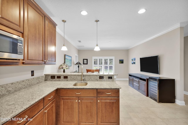 104 Hickory Hill Dr, Saint Augustine, FL 32095 - kitchen with stainless steel microwave, a peninsula, brown cabinets, ornamental molding, and light stone counters