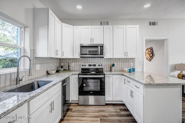 1821 Wofford Ave, Jacksonville, FL 32218 - kitchen with stainless steel appliances, a sink, a peninsula, white cabinets, and a textured ceiling
