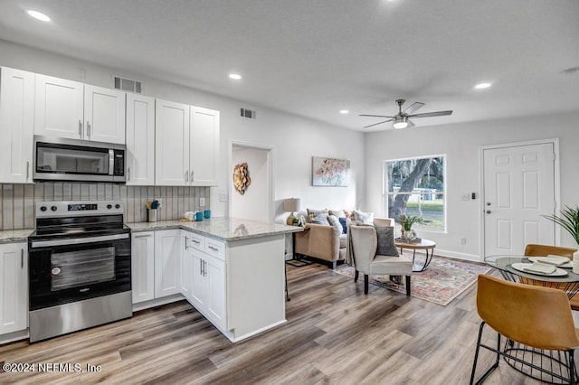 1821 Wofford Ave, Jacksonville, FL 32218 - kitchen with appliances with stainless steel finishes, a peninsula, tasteful backsplash, white cabinetry, and ceiling fan