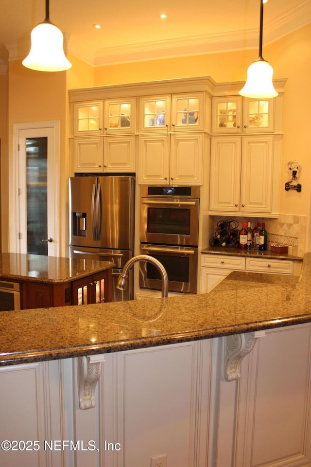 204 Stonewell Dr, Saint Johns, FL 32259 - kitchen featuring appliances with stainless steel finishes, ornamental molding, dark stone counters, glass insert cabinets, and hanging light fixtures
