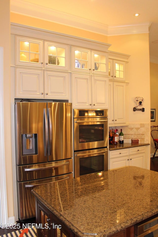 204 Stonewell Dr, Saint Johns, FL 32259 - kitchen featuring stainless steel appliances, dark stone counters, crown molding, white cabinets, and glass insert cabinets