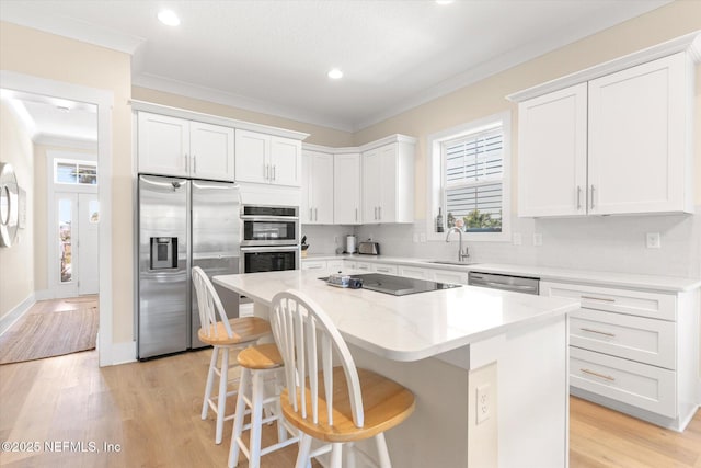 125 5th St, Saint Augustine, FL 32080 - kitchen with stainless steel appliances, a sink, a kitchen island, a kitchen breakfast bar, and crown molding