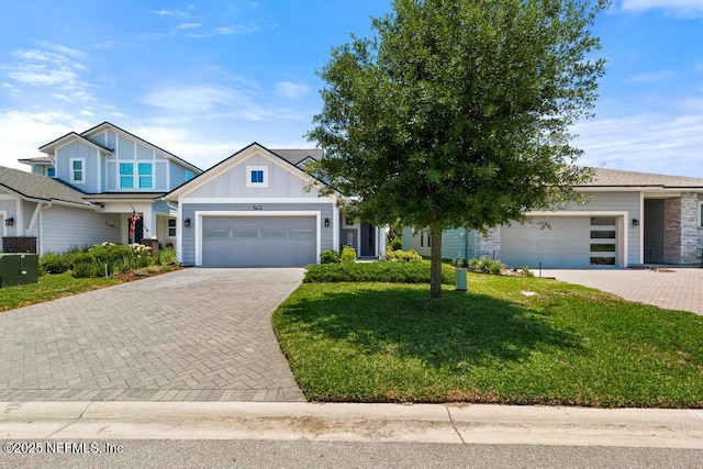 9789 Intellect Trl, Jacksonville, FL 32256 - view of front of home featuring board and batten siding, a garage, decorative driveway, and a front yard