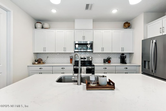 9789 Intellect Trl, Jacksonville, FL 32256 - kitchen featuring appliances with stainless steel finishes, backsplash, white cabinets, and a sink