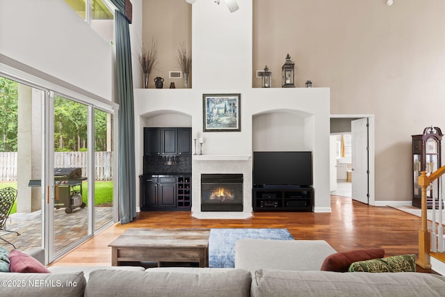 1159 Eastwood Branch Dr, Saint Johns, FL 32259 - living room with a high ceiling, wood finished floors, stairs, a glass covered fireplace, and baseboards