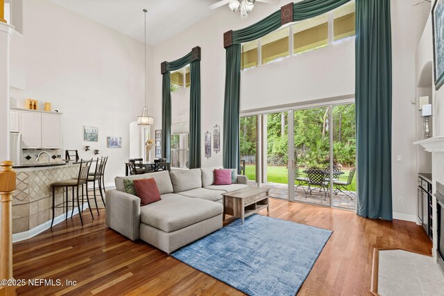 1159 Eastwood Branch Dr, Saint Johns, FL 32259 - living room with a high ceiling, wood finished floors, a fireplace with flush hearth, ceiling fan, and baseboards
