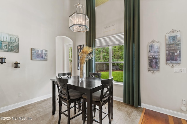 1159 Eastwood Branch Dr, Saint Johns, FL 32259 - dining space featuring arched walkways, baseboards, wood finished floors, a chandelier, and a high ceiling